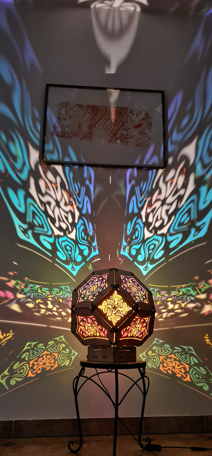 Illuminated kaleidoscope-style shadow lamp with a geometric mushroom design projecting colorful patterns on walls and ceiling.