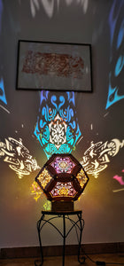 Illuminated kaleidoscope-style shadow lamp with a geometric mushroom design projecting colorful patterns on walls and ceiling.