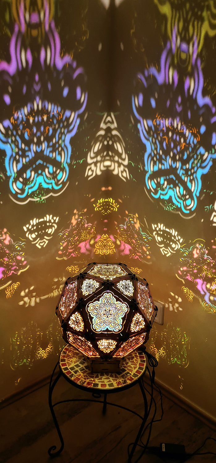 A colorful geometric patterned lamp casts shadows on a wall, with intricate designs created by the interplay of light and shadow.