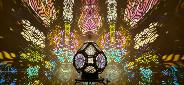 A colorful shadow lamp projecting intricate geometric patterns on a wall, with the lamp in the foreground.