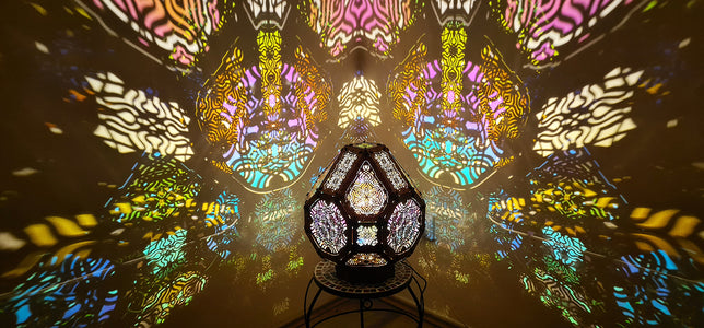A colorful shadow lamp projecting intricate geometric patterns on a wall, with the lamp in the foreground.