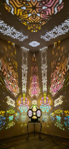 A colorful shadow lamp projecting intricate geometric patterns on a wall, with the lamp in the foreground.