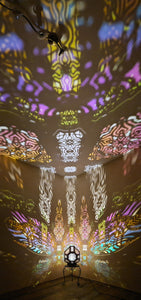 A colorful shadow lamp projecting intricate geometric patterns on a wall, with the lamp in the foreground.