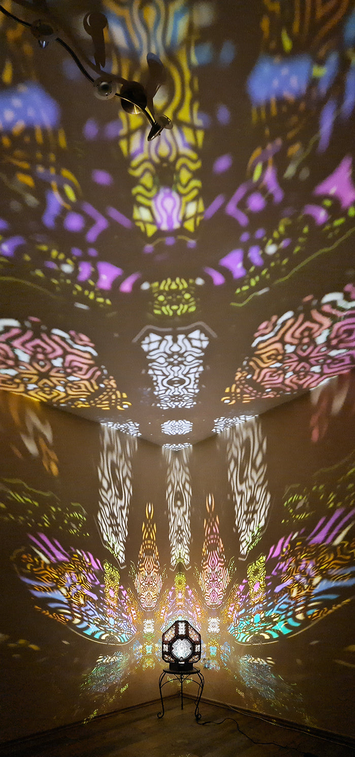 A colorful shadow lamp projecting intricate geometric patterns on a wall, with the lamp in the foreground.