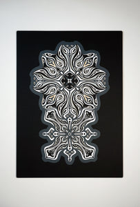 Monochrome layered paper artwork titled Metamorphs, made of intricate geometric mandalas that reveal totemic faces.
