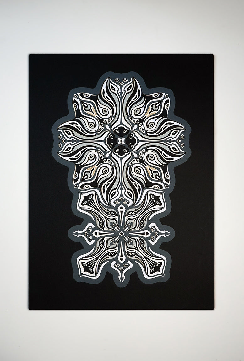 Monochrome layered paper artwork titled Metamorphs, made of intricate geometric mandalas that reveal totemic faces.