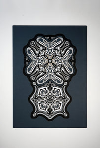 Monochrome layered paper artwork titled Metamorphs, made of intricate geometric mandalas that reveal totemic faces.