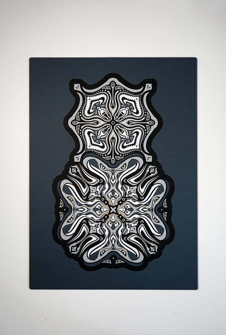 Monochrome layered paper artwork titled Metamorphs, made of intricate geometric mandalas that reveal totemic faces.