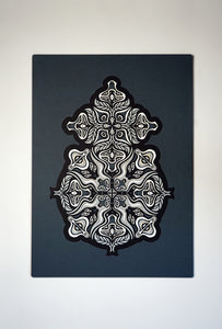 Monochrome layered paper artwork from the Metamorphs series, featuring interlocking mandalas that form hidden animal and spirit faces.
