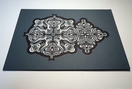 Monochrome layered paper artwork from the Metamorphs series, featuring interlocking mandalas that form hidden animal and spirit faces.