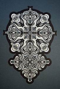 Monochrome layered paper artwork from the Metamorphs series, featuring interlocking mandalas that form hidden animal and spirit faces.