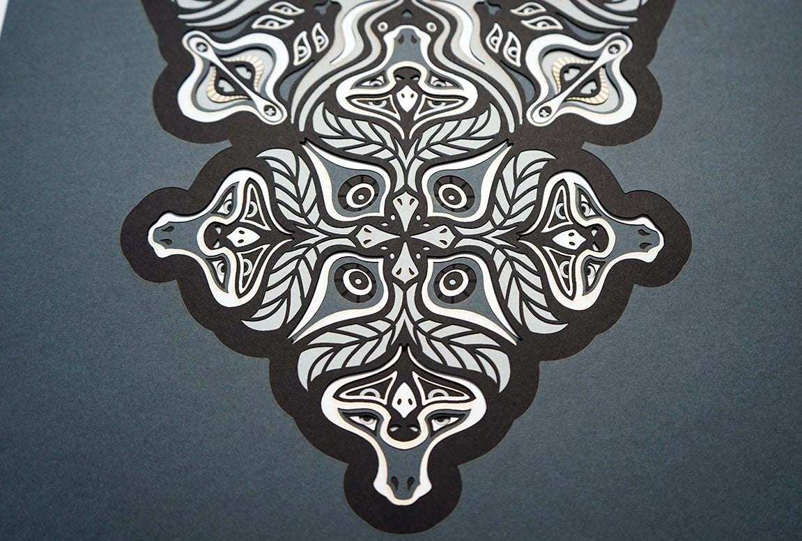 Monochrome layered paper artwork from the Metamorphs series, featuring interlocking mandalas that form hidden animal and spirit faces.