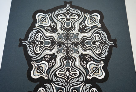 Monochrome layered paper artwork from the Metamorphs series, featuring interlocking mandalas that form hidden animal and spirit faces.