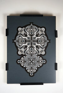 Monochrome layered paper artwork from the Metamorphs series, featuring interlocking mandalas that form hidden animal and spirit faces.