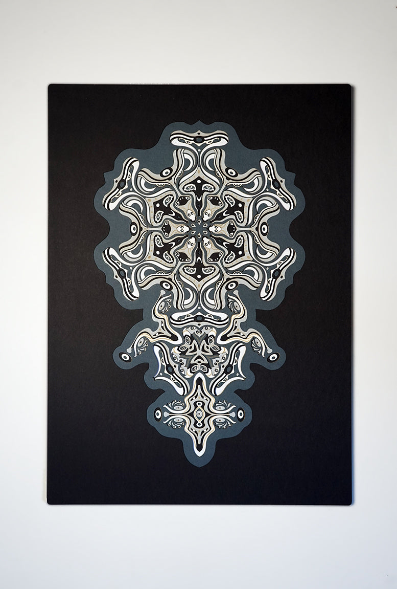 Intricate monochrome paper layers arranged in a mandala structure, creating emerging spirit faces and abstract creatures.