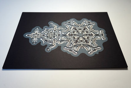 Intricate monochrome paper layers arranged in a mandala structure, creating emerging spirit faces and abstract creatures.