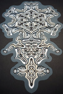 Intricate monochrome paper layers arranged in a mandala structure, creating emerging spirit faces and abstract creatures.