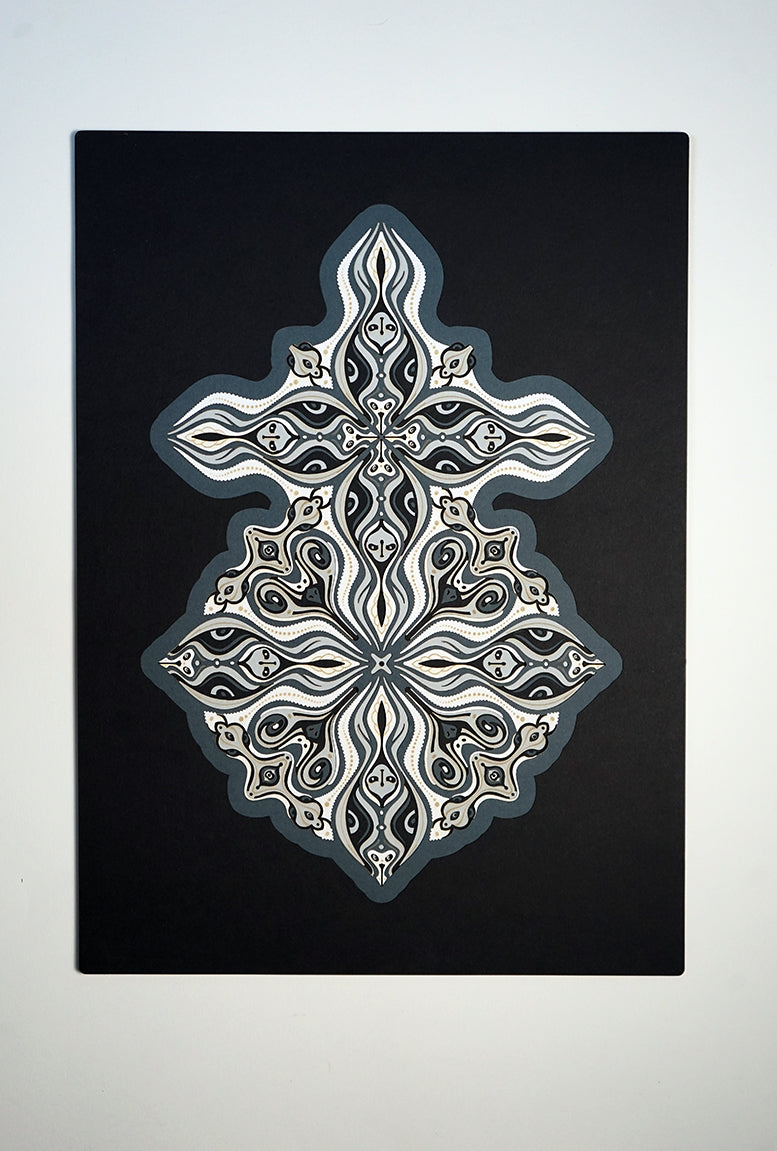 Layered grayscale paper forming symmetrical mandala patterns that reveal subtle, mask-like faces from the Metamorphs series