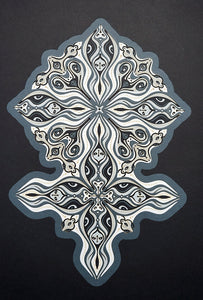 Layered grayscale paper forming symmetrical mandala patterns that reveal subtle, mask-like faces from the Metamorphs series