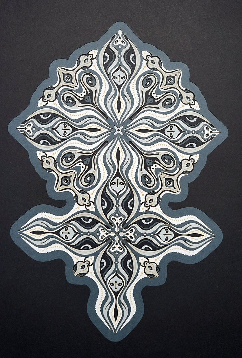 Layered grayscale paper forming symmetrical mandala patterns that reveal subtle, mask-like faces from the Metamorphs series