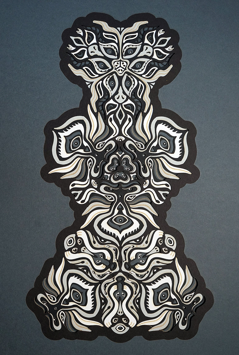 Black and white layered paper mandala with emerging animal spirit faces, part of the Metamorphs collection.