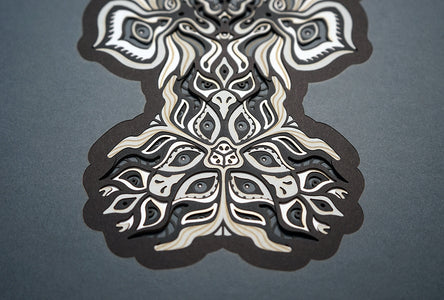 Black and white layered paper mandala with emerging animal spirit faces, part of the Metamorphs collection.