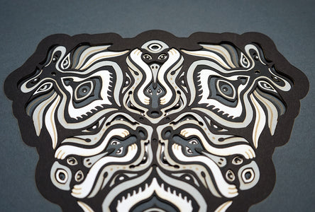 Black and white layered paper mandala with emerging animal spirit faces, part of the Metamorphs collection.