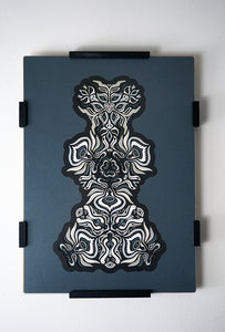 Black and white layered paper mandala with emerging animal spirit faces, part of the Metamorphs collection.