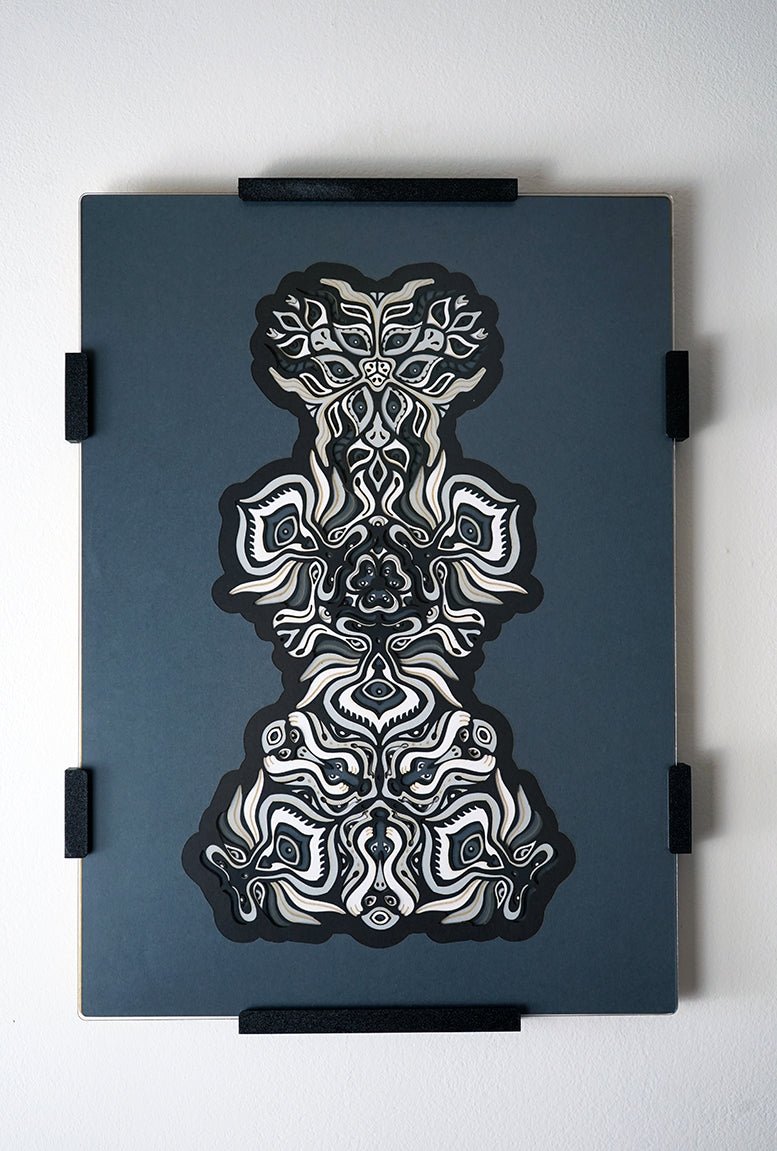 Black and white layered paper mandala with emerging animal spirit faces, part of the Metamorphs collection.