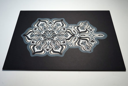 Complex black and white paper layers forming interconnected mandalas that hide subtle morphing faces.