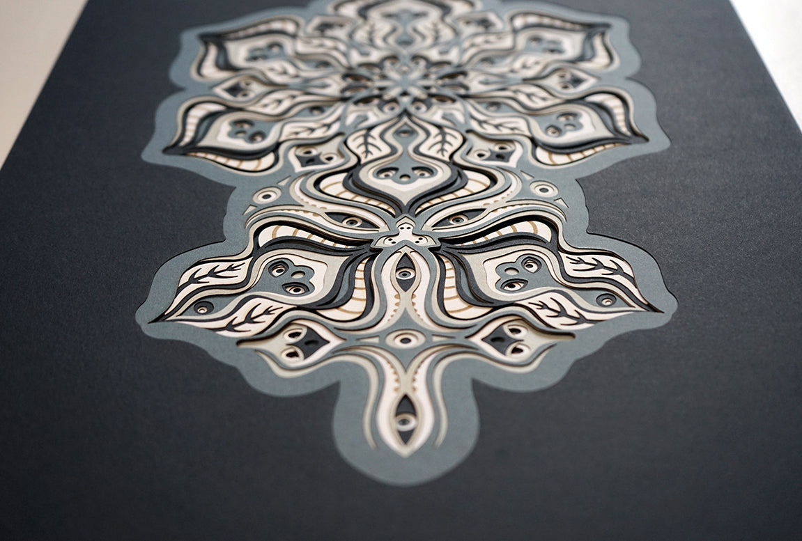 Complex black and white paper layers forming interconnected mandalas that hide subtle morphing faces.