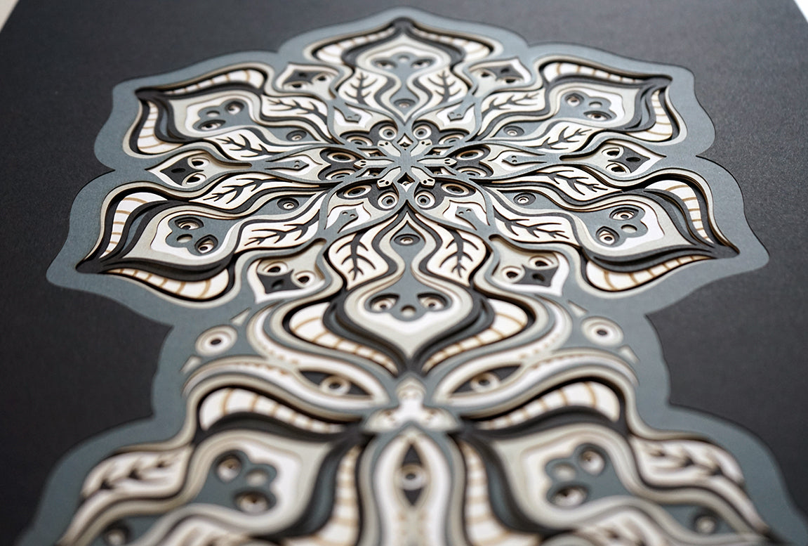 Complex black and white paper layers forming interconnected mandalas that hide subtle morphing faces.