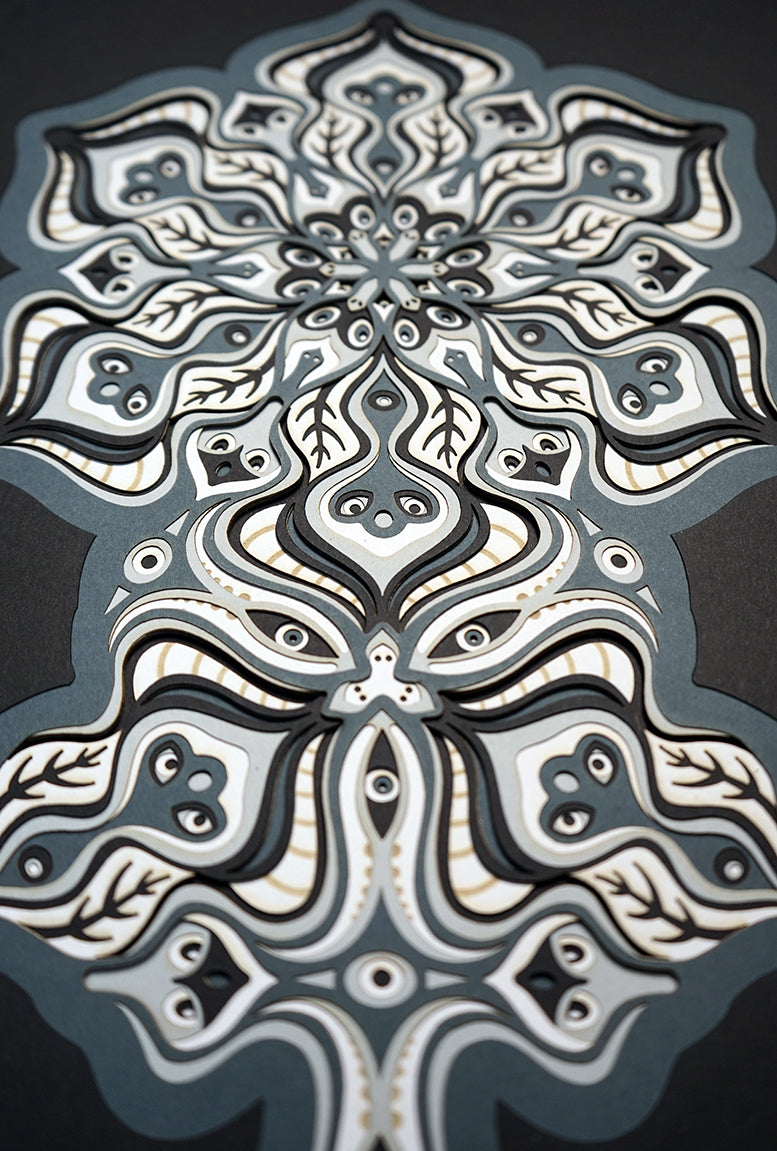 Complex black and white paper layers forming interconnected mandalas that hide subtle morphing faces.