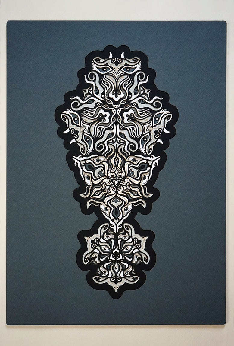 Geometric mandala made of layered grayscale paper, revealing masked spirit figures within the patterns.