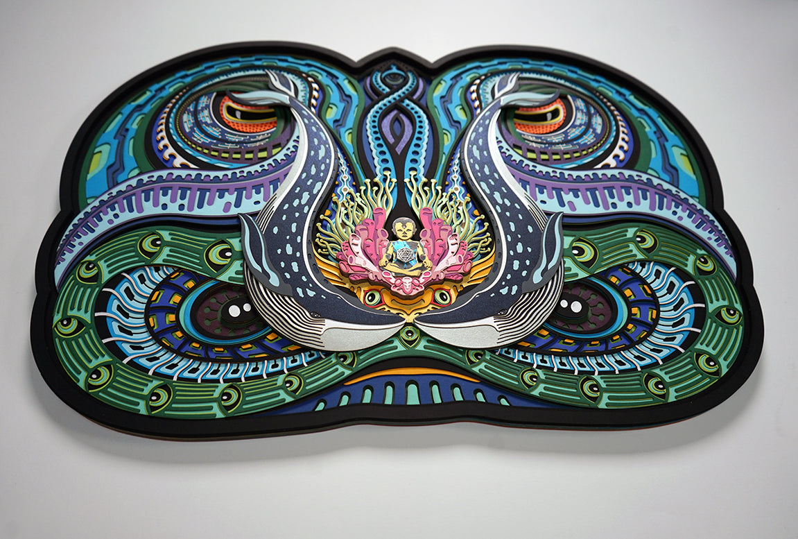 Layered paper art of infant on coral throne with whales and ocean patterns, symbolizing life’s origin and unity.