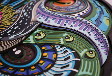 Layered paper art of infant on coral throne with whales and ocean patterns, symbolizing life’s origin and unity.