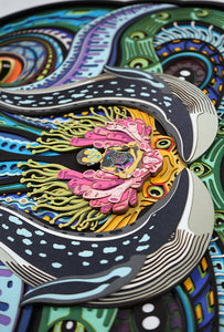 Layered paper art of infant on coral throne with whales and ocean patterns, symbolizing life’s origin and unity.