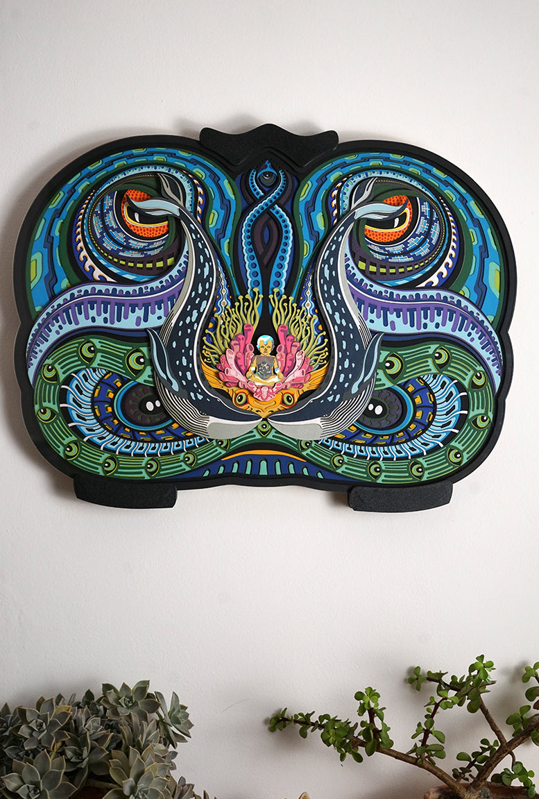 Layered paper art of infant on coral throne with whales and ocean patterns, symbolizing life’s origin and unity.