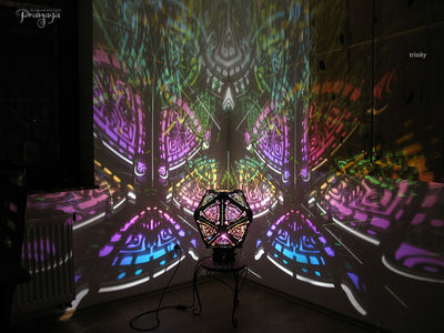 A colorful shadow lamp with a three-petal flower design, projecting vibrant rainbow shadows on the wall