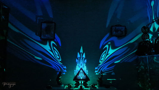 A colorful shadow lamp with a geometric design, featuring triangular sides and a pyramid shape, projecting a vibrant mushroom pattern on a wall.