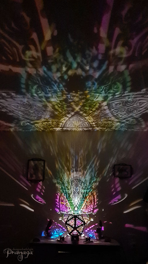 A colorful shadow lamp with a three-petal flower design, projecting vibrant rainbow shadows on the wall