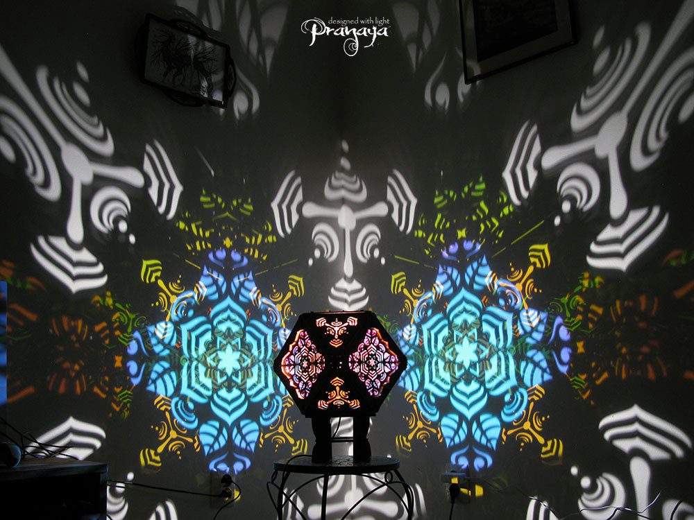 A colorful kaleidoscopic shadow lamp with a geometric pattern, showcasing a cuboctahedron shape with intricate cut-outs, mounted on a stand.