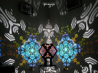 A colorful kaleidoscopic shadow lamp with a geometric pattern, showcasing a cuboctahedron shape with intricate cut-outs, mounted on a stand.