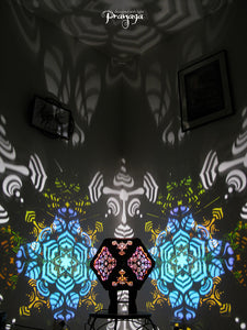 A colorful kaleidoscopic shadow lamp with a geometric pattern, showcasing a cuboctahedron shape with intricate cut-outs, mounted on a stand.