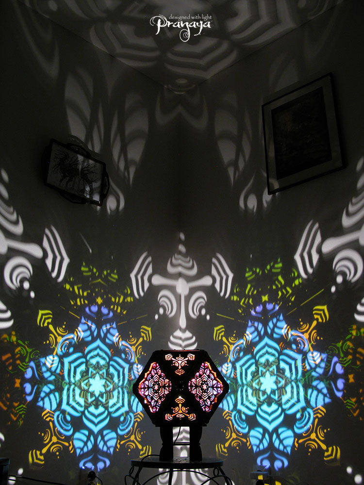 A colorful kaleidoscopic shadow lamp with a geometric pattern, showcasing a cuboctahedron shape with intricate cut-outs, mounted on a stand.